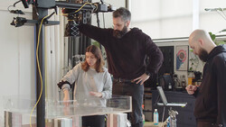 Three people gathered around a light table examining photographic prints in a studio setting.