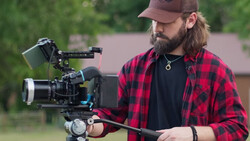 Cinematographer operating a cinema camera on a gimbal stabilizer outdoors.