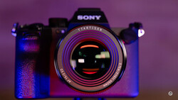 Sony camera with Ttartisan lens against purple and blue gradient lighting with shallow depth of field.