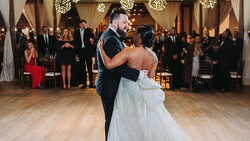 Bride and groom dancing together during their first dance at an elegant indoor wedding reception.