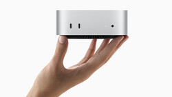 Hand holding a compact silver and black desktop computer against a white background.