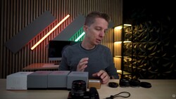 Photographer demonstrating camera lenses and accessories on a table during a product review.