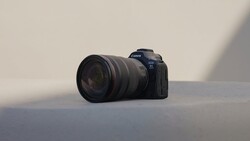 Canon EOS R5 mirrorless camera with attached telephoto lens on neutral surface.