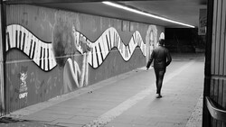 Runner jogging through an underpass with large-scale wavy piano key mural art.