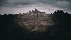 Dramatic badlands landscape with distinctive peaked formations rising against stormy sky.
