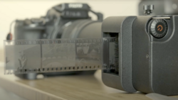 Compact digital camera next to 35mm film roll and vintage film camera in soft studio lighting.