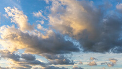 Dramatic sky at sunset with layered clouds illuminated by golden and blue light.