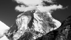 Snow-covered mountain peaks with dramatic vertical columnar formations beneath a partly cloudy sky.