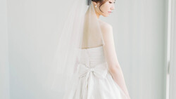 Bride in profile wearing a strapless white wedding dress with a bow detail and delicate veil.