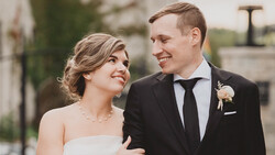 Bride and groom smiling at each other outdoors during their wedding day.