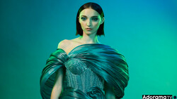 Woman in turquoise off-shoulder gown against monochromatic teal background.