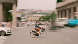 Cyclist riding through urban plaza with motion blur effect surrounding the figure.