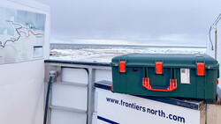 Green and red toolbox on a white van with coastal landscape visible in background.