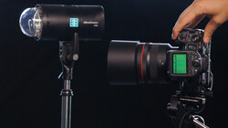 Professional monolight and DSLR camera with telephoto lens on black background.
