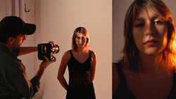 Filmmaker operating a vintage camera while photographing a woman in a black tank top against a white wall.
