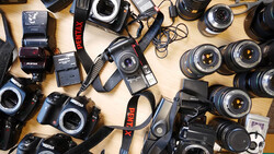 Collection of Pentax film cameras, lenses, flashes, and accessories arranged on a wooden surface.