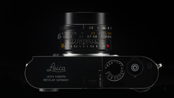 Top-down view of a Leica rangefinder camera with mounted lens against a black background.