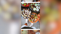 Overhead view of multiple dishes with food arranged on a gray surface, shot from above with person's feet visible.