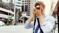 Photographer holding vintage camera to face on urban street surrounded by tall buildings.