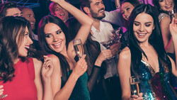 Group of people in formal attire celebrating with champagne glasses at a nightclub or party venue.