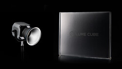 LED studio light with reflector head next to a rectangular branded box on black background.