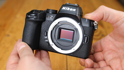 Nikon Z mirrorless camera held in hands, showing open sensor with white mirror box frame visible.