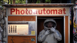 Vintage photo booth with astronaut figure in helmet touching its face through the window.