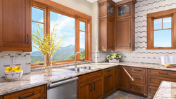 Luxury kitchen with wood cabinetry, granite countertops, and expansive windows overlooking mountains.