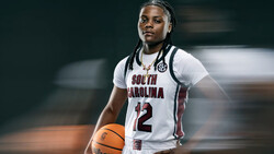 Basketball player wearing South Carolina white jersey number 12 holding a basketball.
