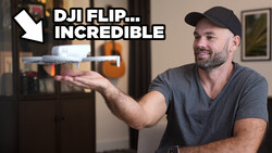 Man holding a small drone while gesturing toward it in an indoor setting.