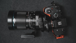Mirrorless camera with macro lens and extension tubes arranged on dark surface.