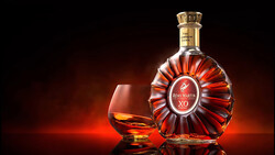 Cognac bottle and snifter glass against warm amber-lit background.