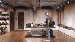 Visitor examines vintage cameras displayed on central platform in minimalist gallery space.