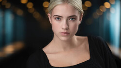 Portrait of a blonde woman with a serious expression against a blurred bokeh background.