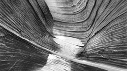 Aerial view of a narrow canyon with striated rock walls and a water channel flowing through the center.