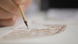 Close-up of a paintbrush with fine bristles applying delicate strokes to textured paper.