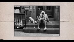 Woman and small dog sitting together on urban building steps in black and white photography.