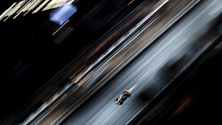Formula One race car captured with motion blur on a diagonal asphalt track.
