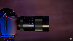 Telephoto lens mounted on blue camera body against purple background.