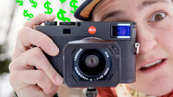 Photographer holding a Leica rangefinder camera with a small LCD screen visible on top.