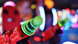 Close-up of a red party horn with green and black coiled paper, with colorful bokeh lights blurred in the background.