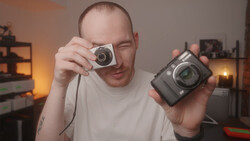 Photographer holding a vintage film camera in one hand and a digital camera in the other.