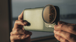 Hands holding a smartphone with dual-lens camera system in landscape orientation.
