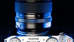 Fujifilm camera body with blue zoom lens showing focal length markings 16-50mm.