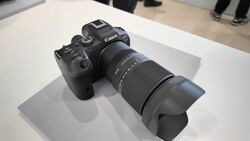 Canon mirrorless camera with telephoto lens mounted on white display surface.