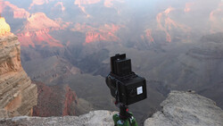 Medium format camera mounted on tripod at Grand Canyon's edge during golden hour sunrise.