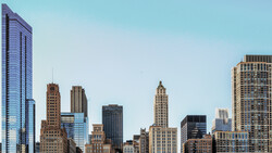 Downtown skyline with mix of historic and modern skyscrapers against clear blue sky.
