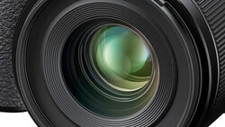 Close-up of a camera lens front element with multi-coated glass and internal lens groups visible.
