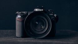 Nikon D200 DSLR camera with attached lens, positioned against a dark background.