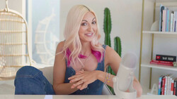 Woman with platinum blonde and pink hair sitting at desk in bright, minimalist home office.